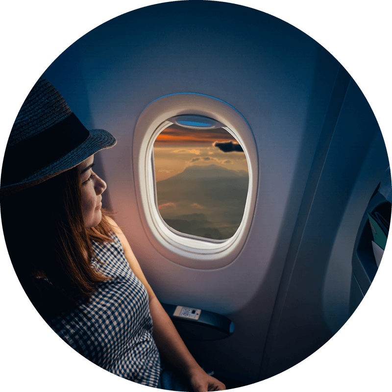 An Eversense user travels with CGM device while wearing a hat relaxes, gazing out an airplane window.